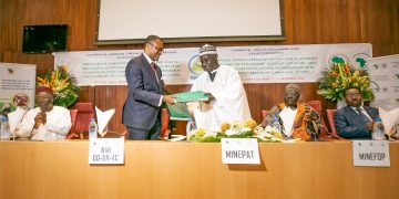 Mey and Bassolé exchange documents after signing the agreements